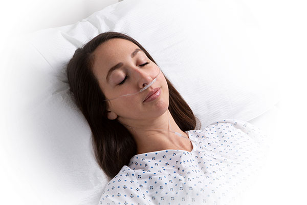 Masimo - Mujer adulta en la cama del hospital con la línea RRc por capnografía NomoLine